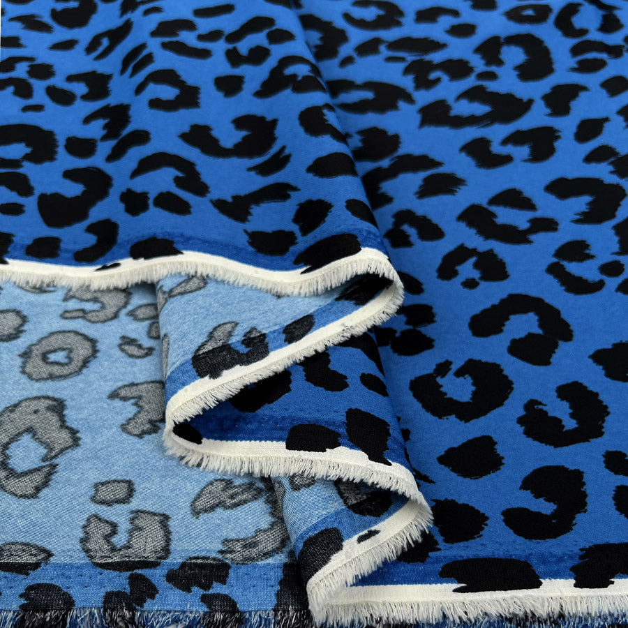Blue stretch twill dress fabric with black leopard print and white fringe edges